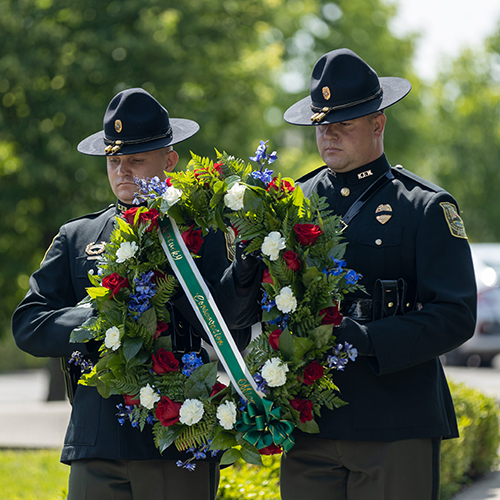 two officers holding up a wreath